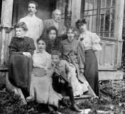 Rakstniece Emīlija Prūsa (1878-1950) - pirmajā rindā pirmā no kreisās, viņas vīrs Ādams Prūsas (stāv otrajā rindā pirmais no kreisās) ap 1906.gadu viesos pie tautas atmodas laikmeta darbinieka Andreja Jankava